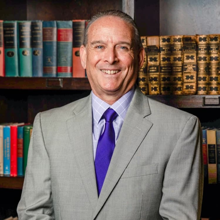 A headshot of David Krassner, smiling in front of vintage books.