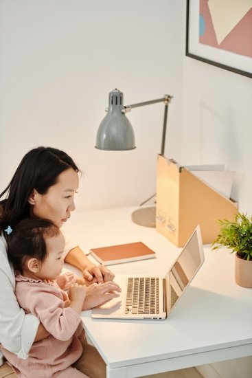 A woman holding her baby while working.